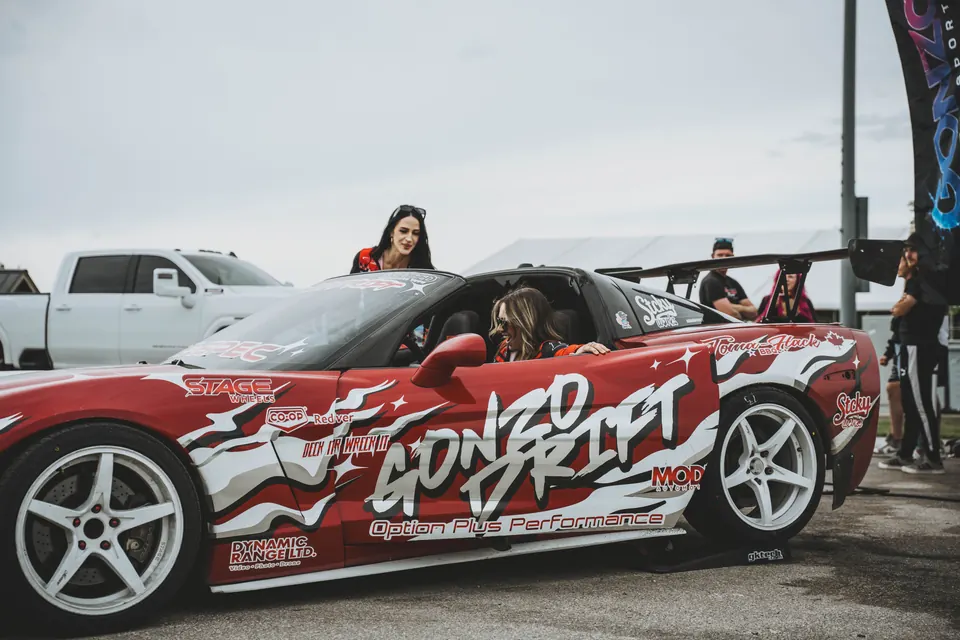 Two women getting into the red and white Gonzo Drift Corvette