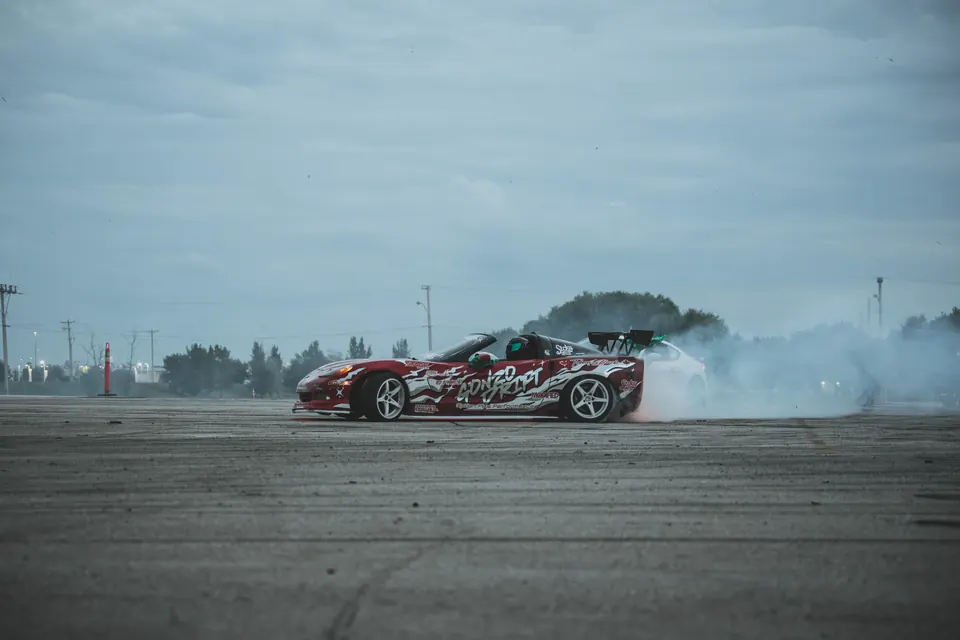 Red and white Corvette drifting through tire smoke